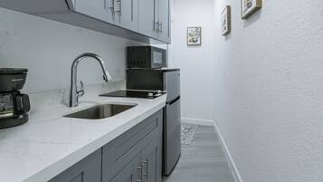 A compact kitchen with a sink, a microwave, and a refrigerator.