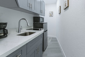 A compact kitchen with a sink, a microwave, and a refrigerator.