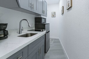 Eine kleine Küche mit Spüle, Mikrowelle und Kühlschrank.