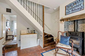 A staircase leading to a loft bedroom with a rustic decor, a vintage stove, and a sign above the fireplace. - Host Stay Silk Weaver s Cottage (Norwich)