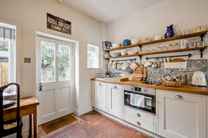 A kitchen with white cabinets, a wooden countertop, and a tiled backsplash. - Host Stay Silk Weaver s Cottage (Norwich)