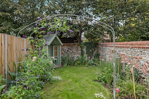 A garden with a wooden fence, a small shed, and a stone wall. - Host Stay Silk Weaver s Cottage (Norwich)