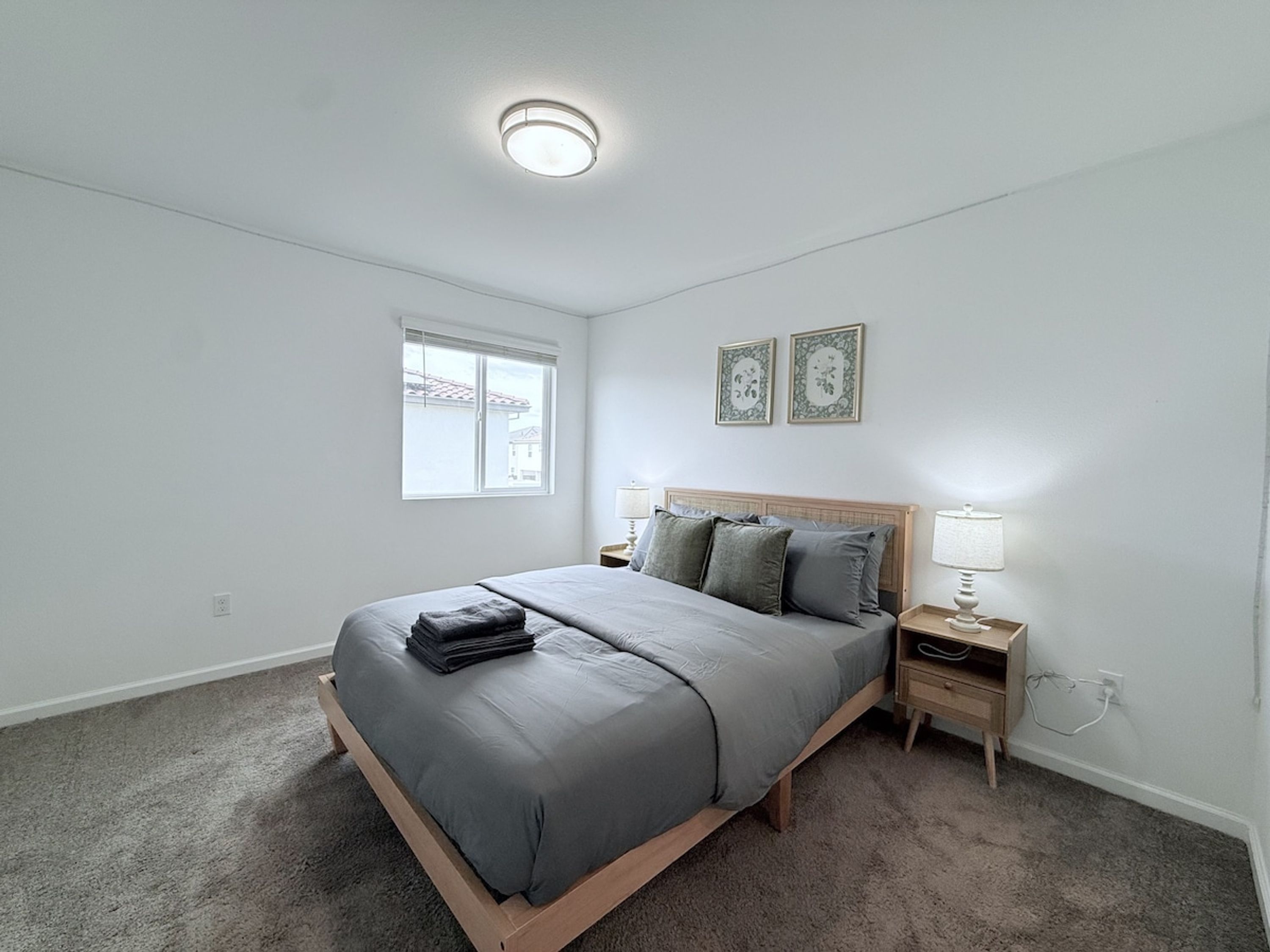 A bedroom with a bed, bedside tables, a window, and a ceiling light.