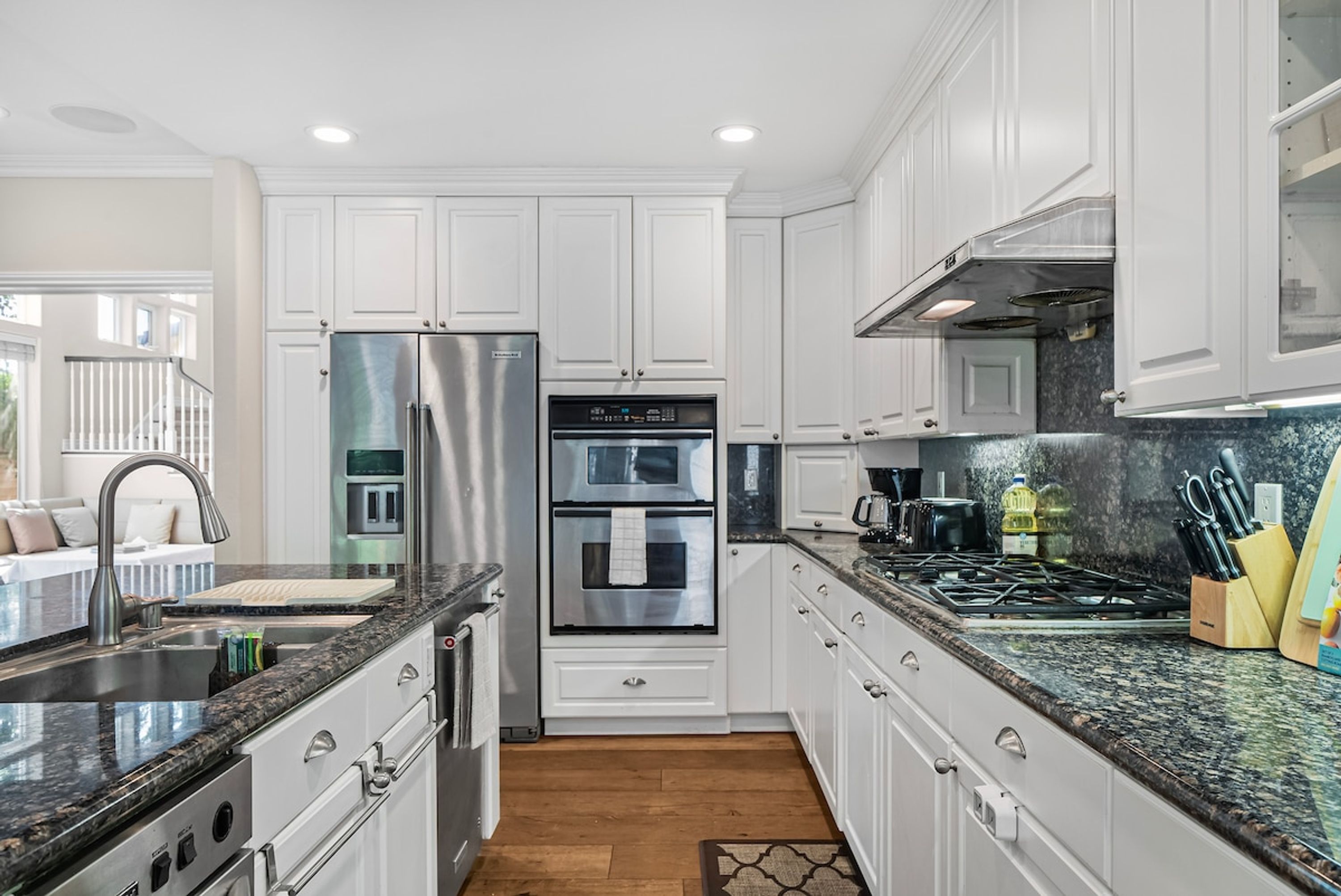A modern kitchen with white cabinetry, stainless steel appliances, and a granite countertop.