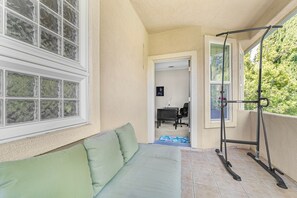 Ein Zimmer mit einem grünen Sofa, einer Klimmzugstange und Blick auf ein bewaldetes Gebiet.