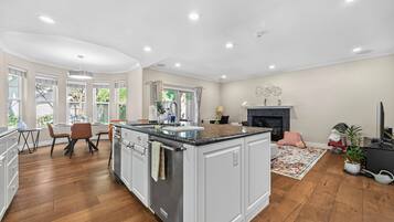 A spacious kitchen with a central island, wooden flooring, and a dining area with a table and chairs.