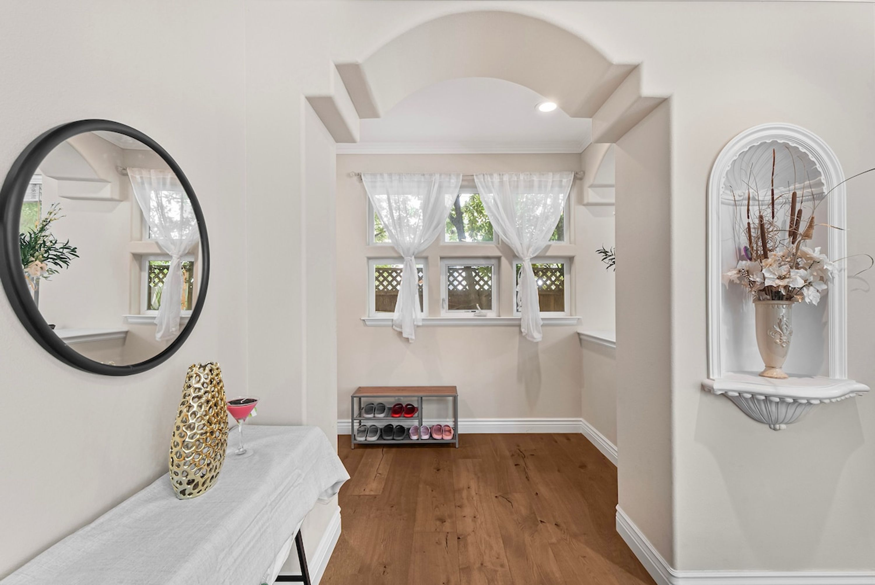 A hallway with a mirror, a shoe rack, and a decorative vase.