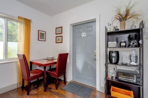 A dining area with a table and chairs, a grey door, and a shelf with kitchen appliances. - 'chez Mercedes Suite' w/ Terrace in North Miami! (North Miami Beach)
