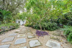 A garden pathway leading to a white building, surrounded by lush greenery and various plants. - 'chez Mercedes Suite' w/ Terrace in North Miami! (North Miami Beach)