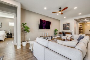 A modern living room with a large grey sofa, a ceiling fan, and a flat-screen TV mounted on the wall. - Gather - Relax - Stay Awhile - Near Ballparks Mts (Goodyear)