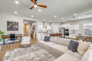 A modern kitchen with white cabinets, stainless steel appliances, and a dining area with a table and chairs. - Gather - Relax - Stay Awhile - Near Ballparks Mts (Goodyear)
