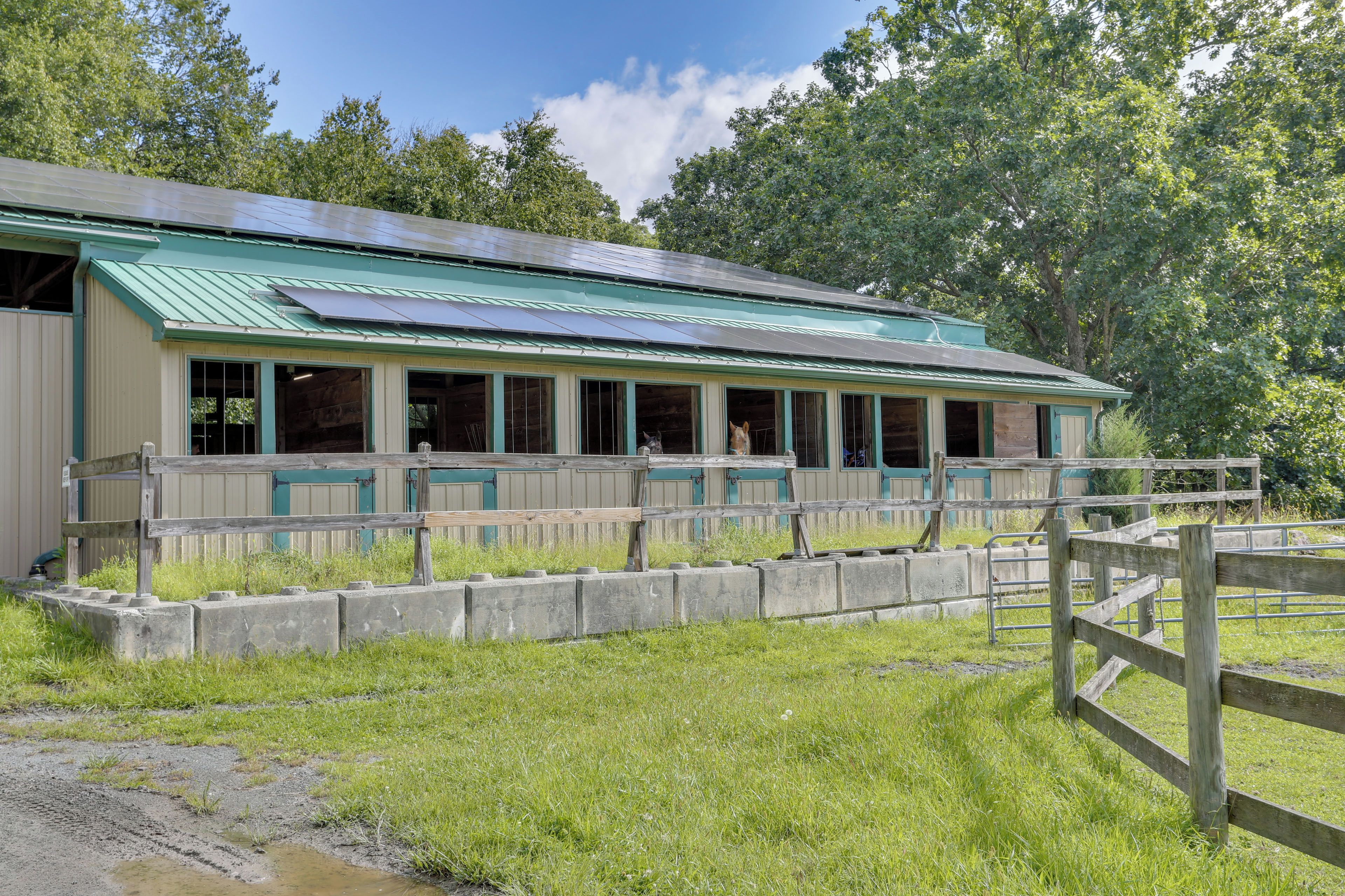 A building with a green roof, large windows, and a wooden fence in front.