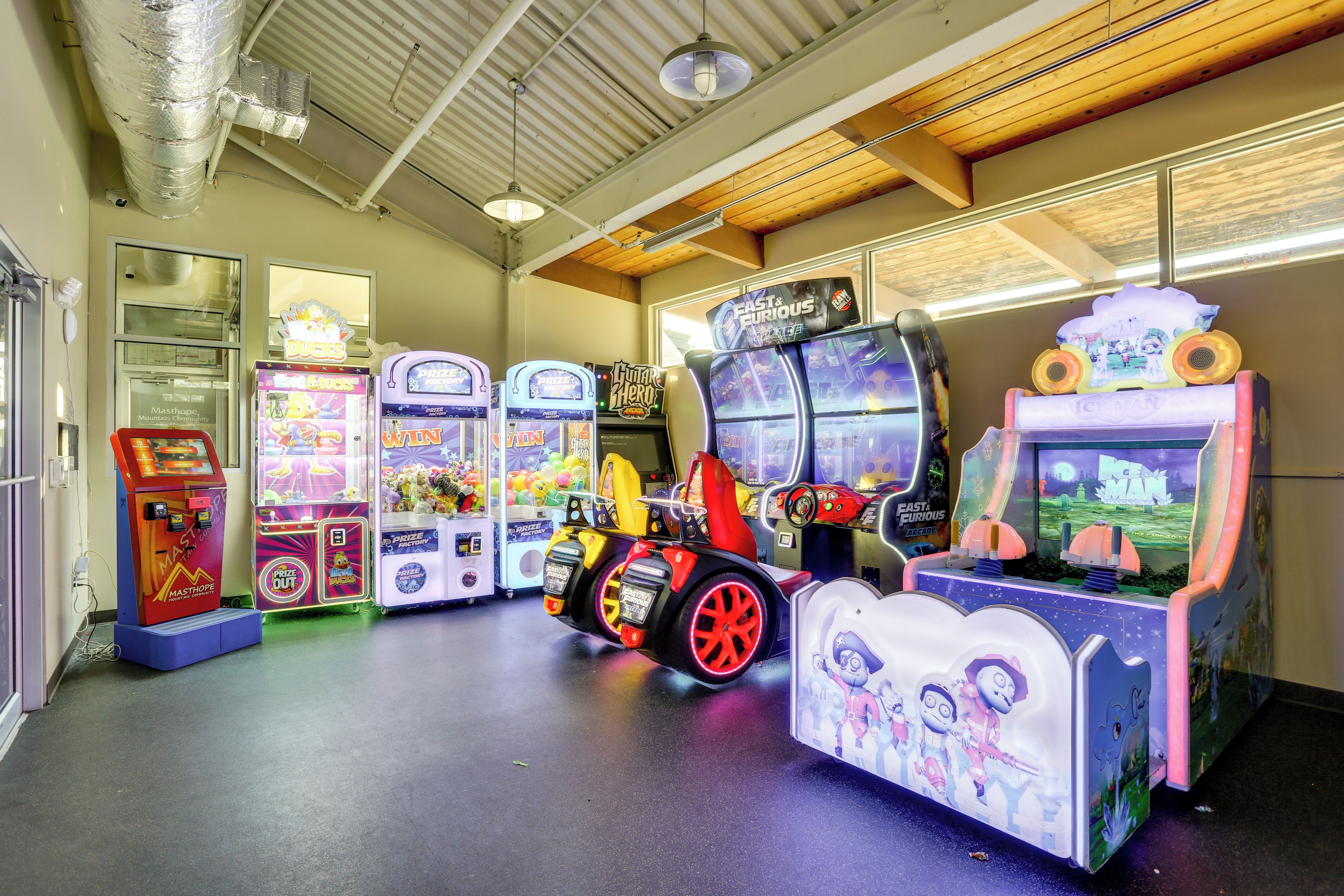 An indoor arcade with claw machines and racing game machines.
