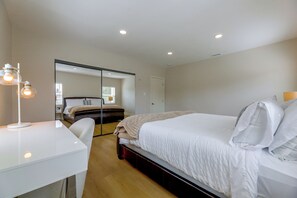 A hotel room with a bed, bedside table, and a mirror.