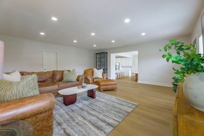 A spacious living room with a leather sofa set, a coffee table, and a large plant.