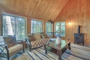 L’intérieur chaleureux d’un chalet avec un canapé, une table et un poêle à bois.
