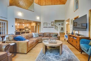 A spacious living area with a large L-shaped sofa, a coffee table, and a television.