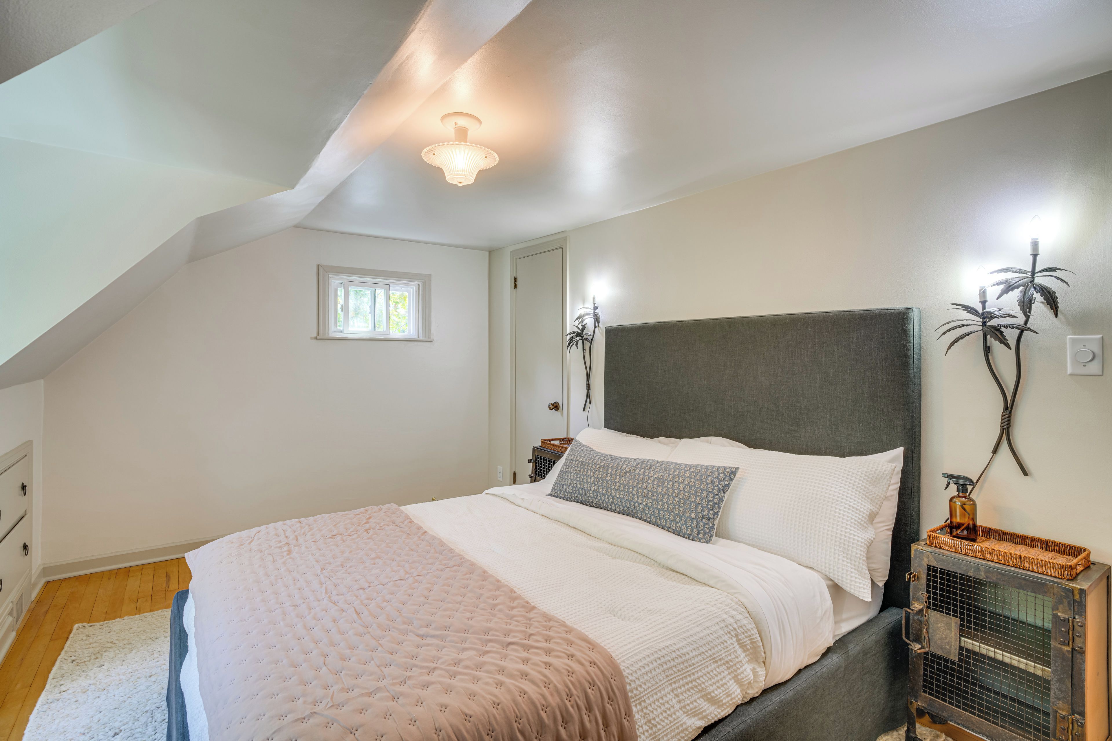 A bedroom with a large bed, a window, a wall-mounted plant, and a radiator.