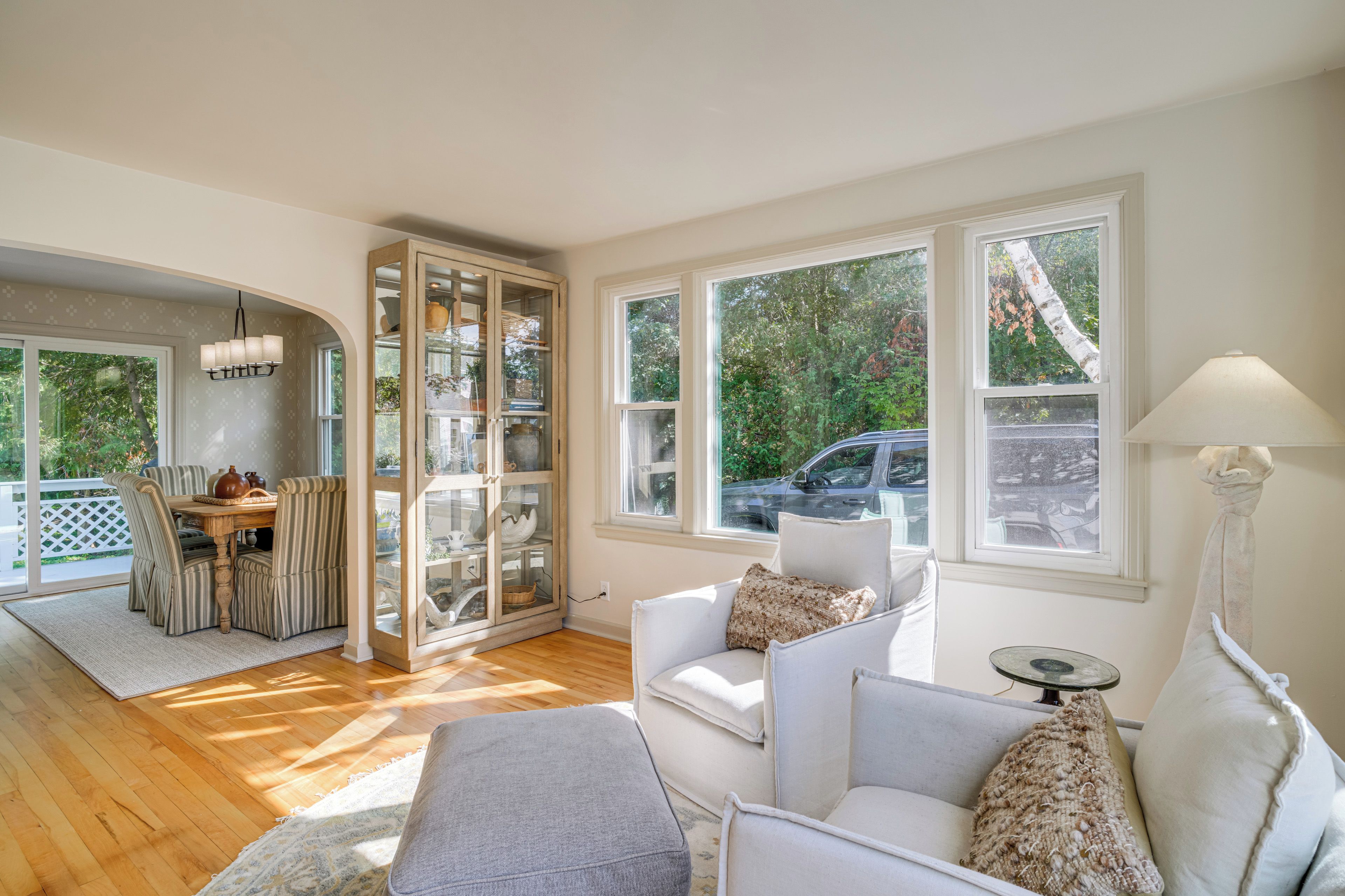 A spacious living area with a dining table, cushioned seating, and large windows offering a view of the outdoors.