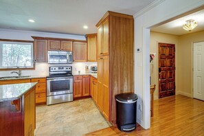 Eine Küche mit Holzausstattung, Edelstahlgeräten und einer Arbeitsplatte aus Granit.