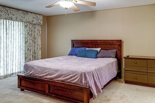 Un dormitorio con una cama de madera, un tocador y un ventilador de techo.