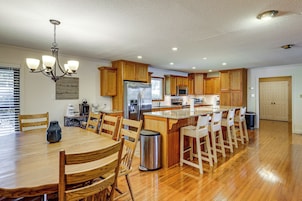A spacious kitchen with wooden cabinets, a stainless steel refrigerator, and a central island with bar stools.