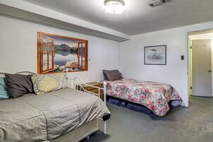 Un dormitorio con cama, mesita de noche, silla, cuadro y puerta.