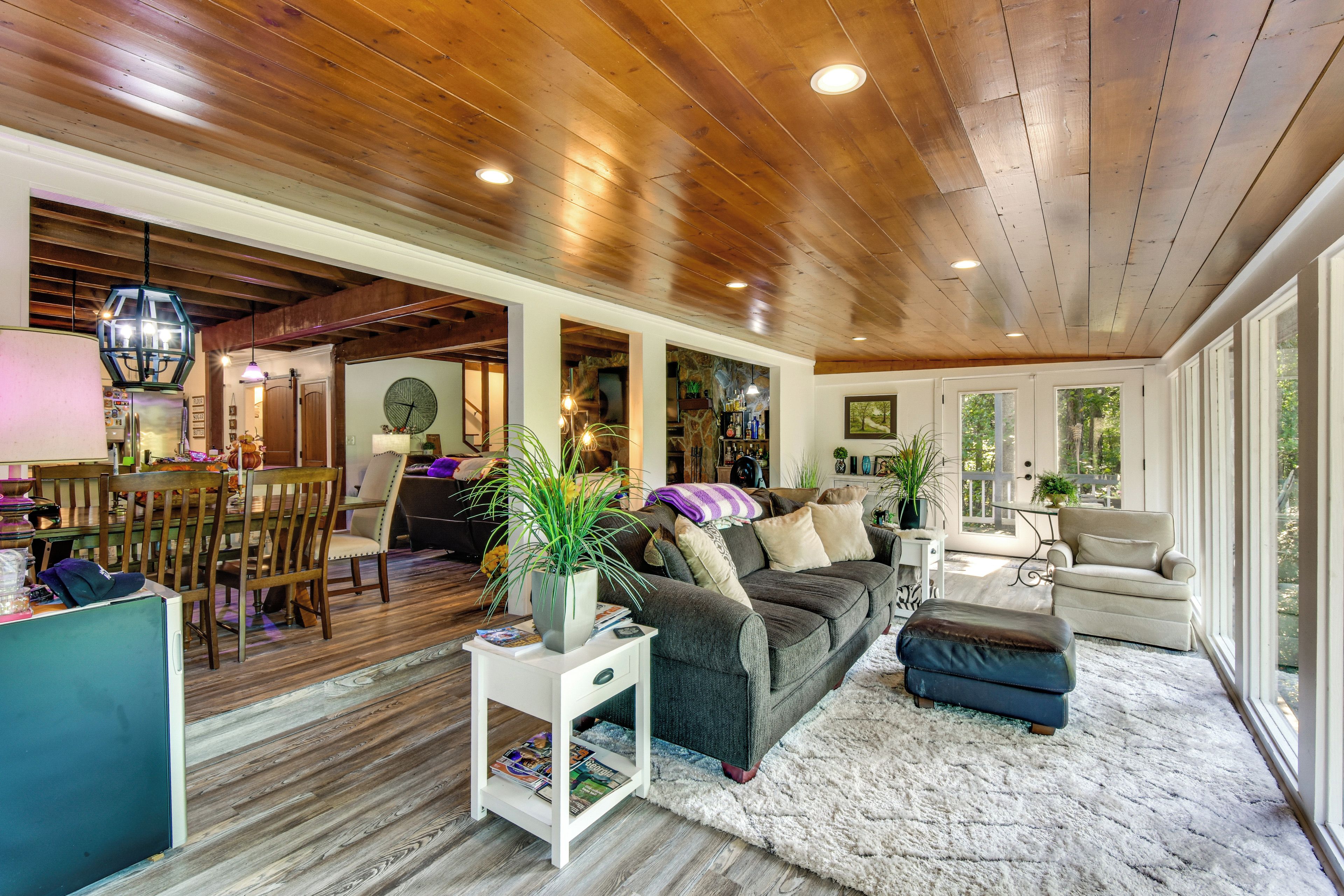 A spacious living area with a wooden ceiling, a sofa, a coffee table, and a dining area with a table and chairs.