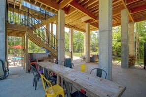 An outdoor covered patio with a wooden table, chairs, and a staircase leading to an upper level. - Play & Unwind! Pass Christian Home < 1 Mi to Gulf (Pass Christian)