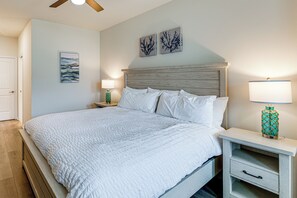 A bedroom with a large bed, two bedside tables, a nightstand, a ceiling fan, and wall art. - 5 Mi to Bethany Beach! Family & Pet-friendly Haven (Ocean View)