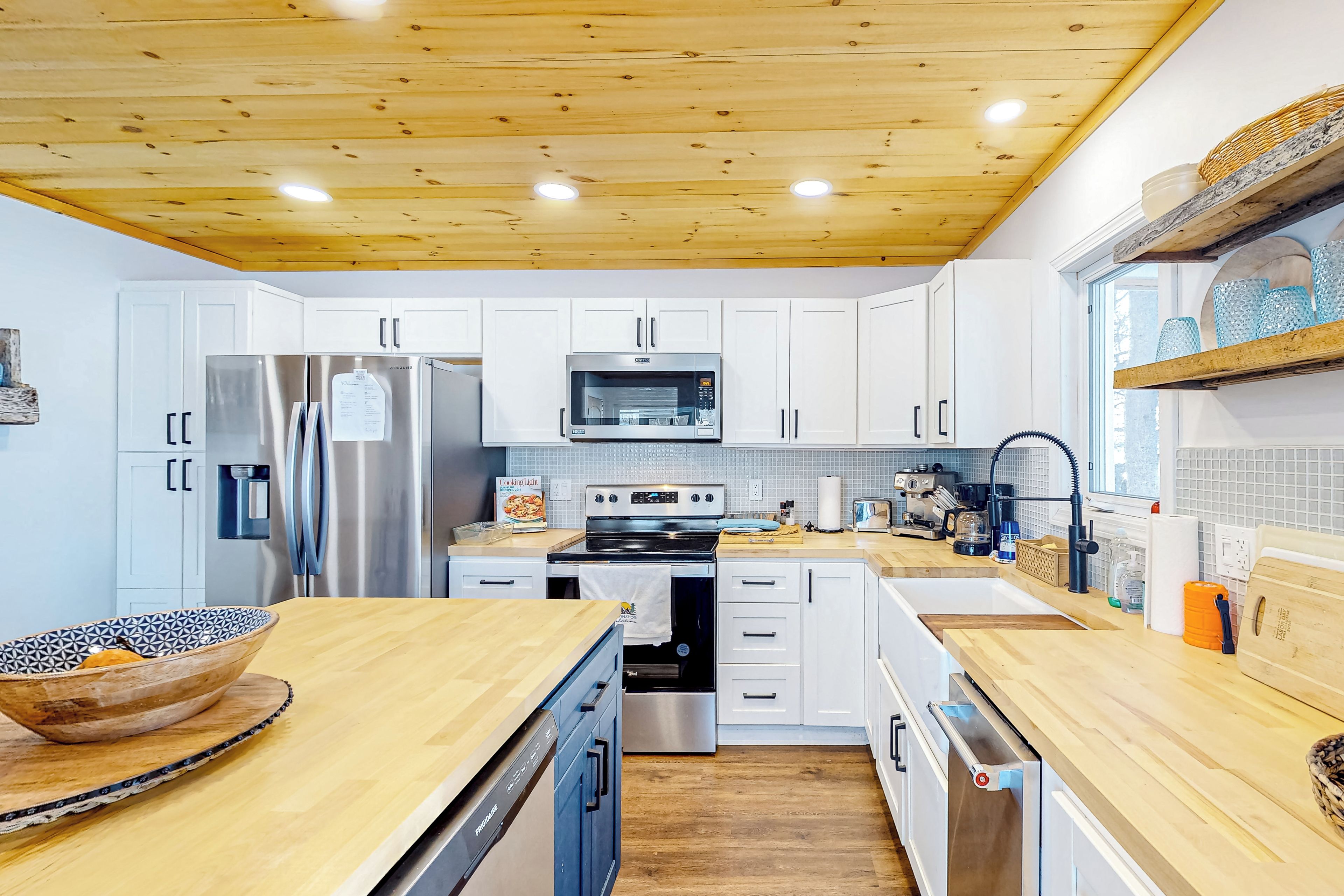 A modern kitchen with white cabinets, stainless steel appliances, and wooden countertops.
