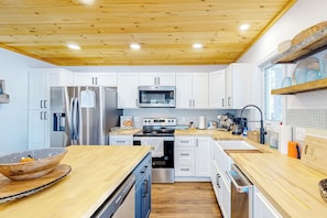 A modern kitchen with white cabinets, stainless steel appliances, and wooden countertops.