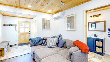 A living room with a grey sofa, wooden ceiling, and a blue cabinet with baskets.