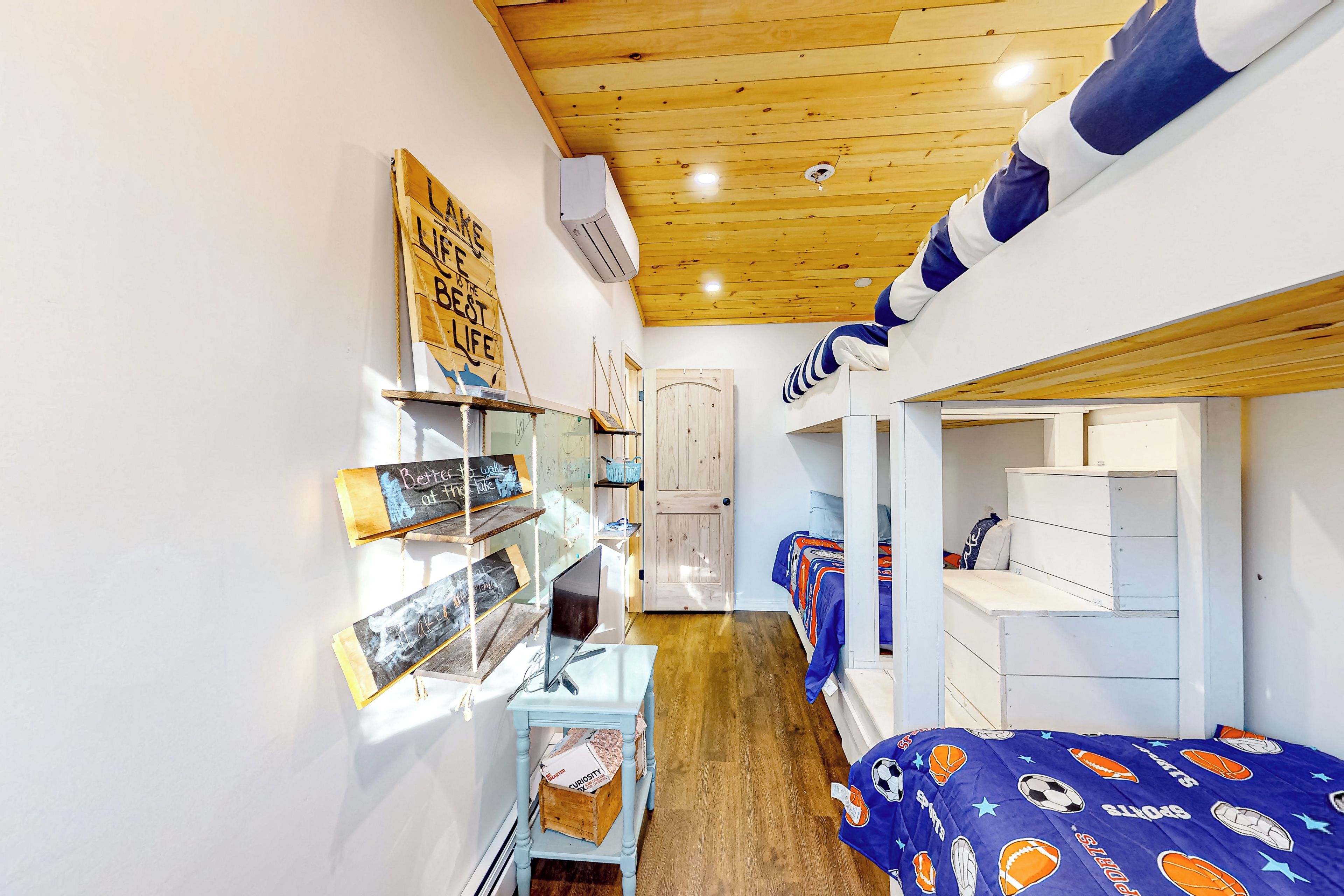A compact room with a bunk bed, a desk with a computer, and a bookshelf.