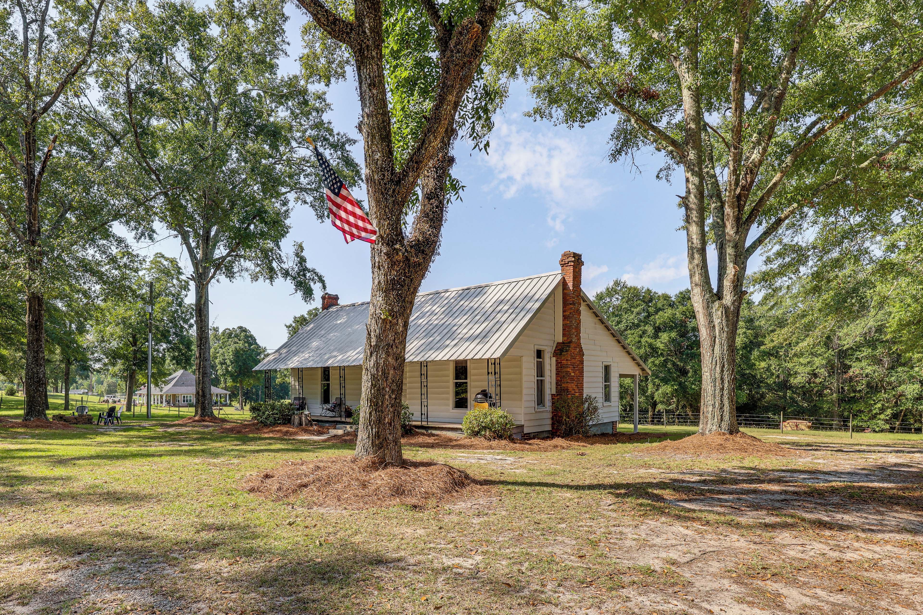 A historic building with a metal roof, surrounded by trees and a grassy area.