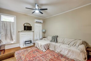 Quarto com cama, ventilador de teto, ar condicionado, aquecedor, janela com cortinas e tapete estampado.