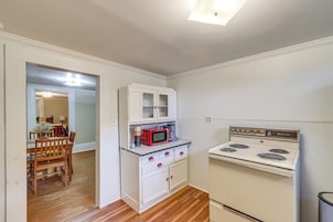 Una cocina compacta con muebles blancos, un microondas rojo y una estufa blanca.