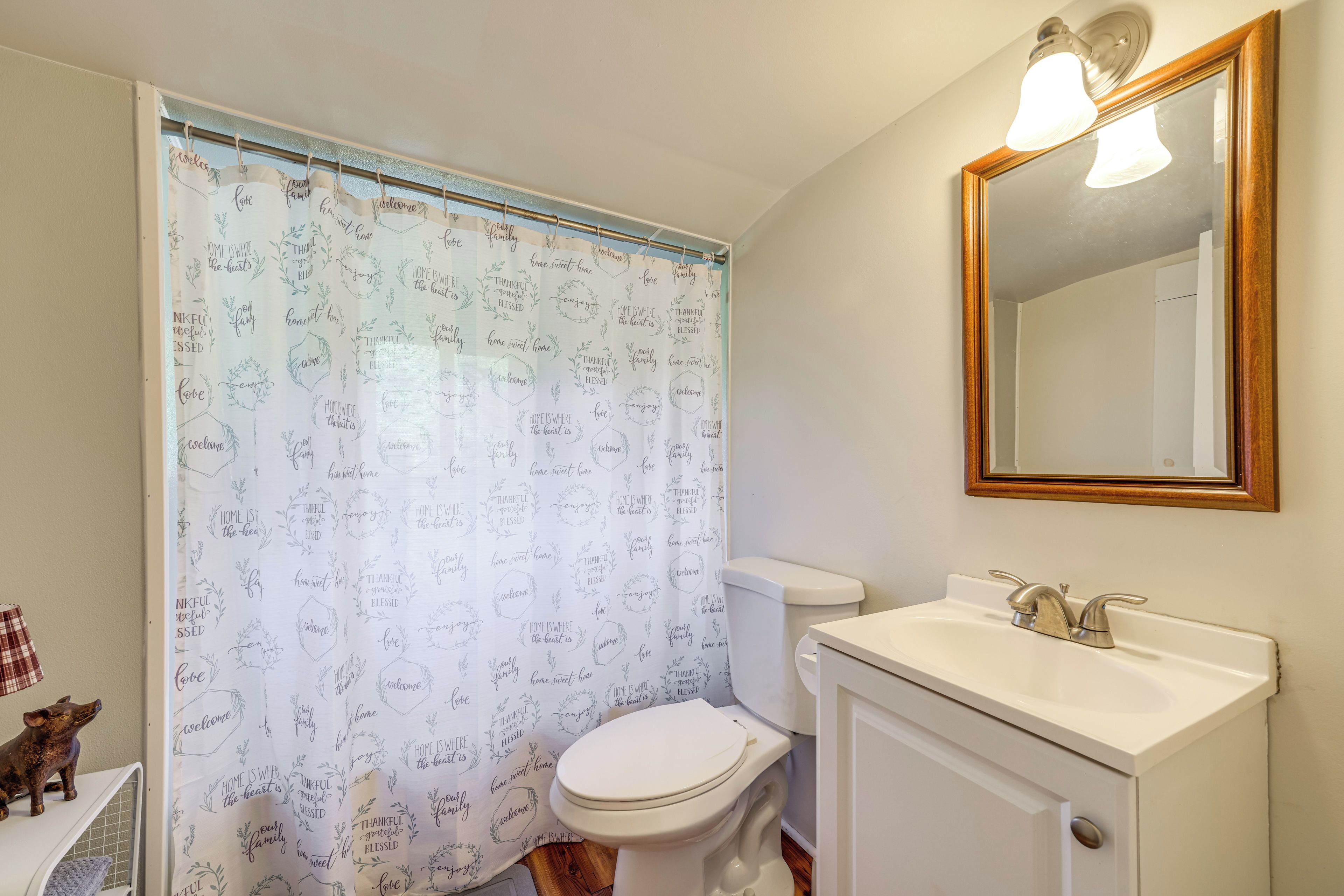 Une salle de bain équipée de toilettes, d’un lavabo et d’un rideau de douche orné de phrases motivantes.