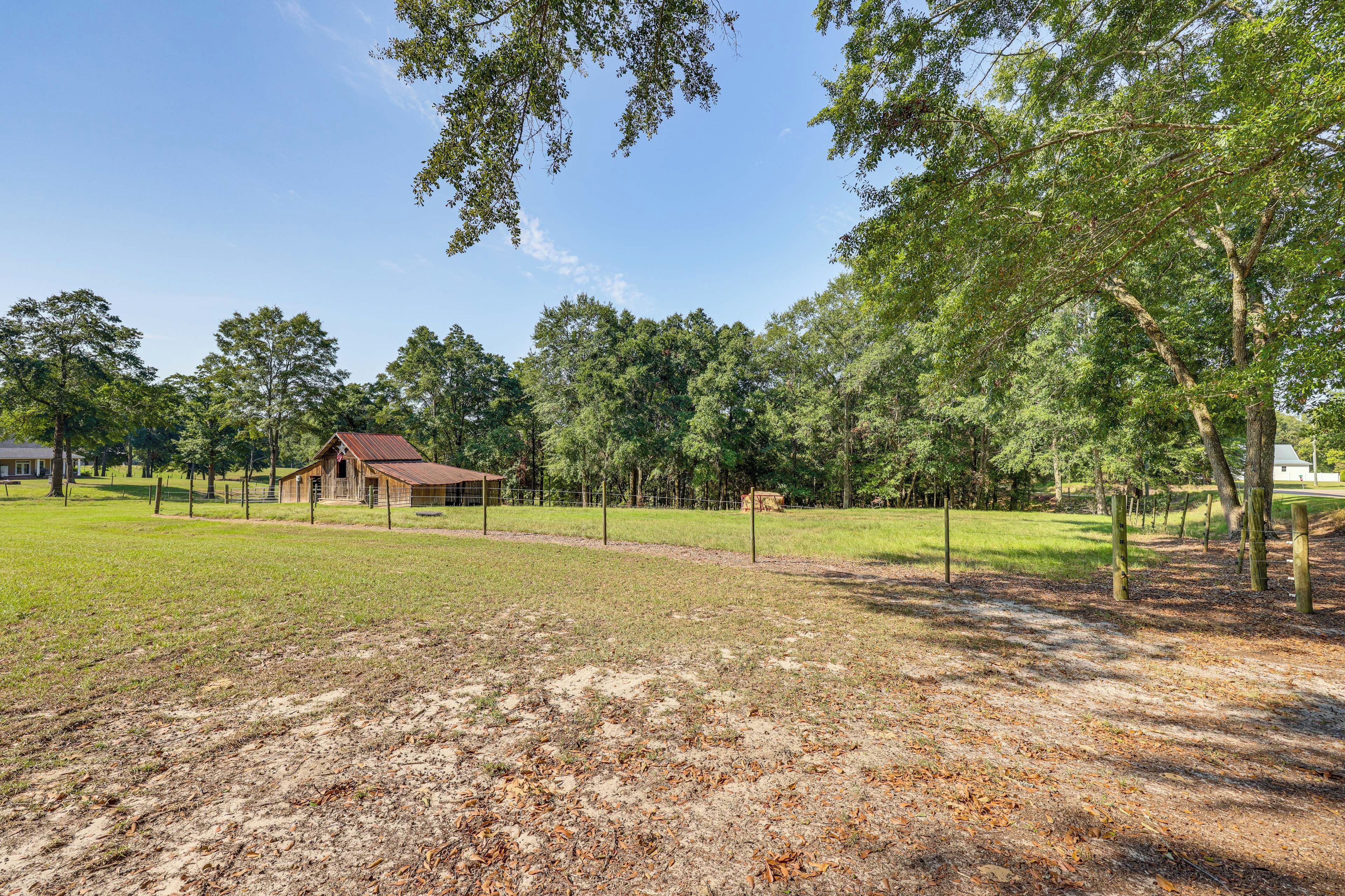 A fenced property with a barn, open grassy areas, and trees.
