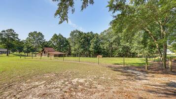 A fenced property with a barn, open grassy areas, and trees.