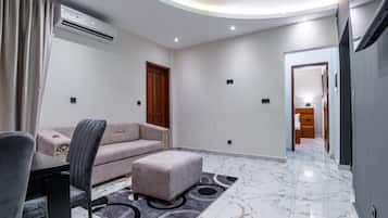 Una sala moderna con un sofá, un reposapiés y una mesa de comedor con sillas.