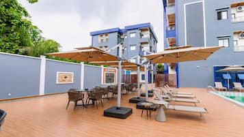 A rooftop terrace with outdoor seating, a pool, and a building with balconies.