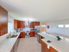 A modern kitchen with wooden cabinets, stainless steel appliances, and a granite countertop. - Sweeping Ocean & Koko Head Views - Ridgetop Home (Honolulu)