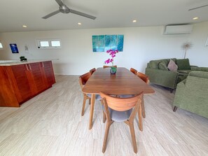 A dining area with a wooden table and chairs, a green sofa, and a ceiling fan. - Sweeping Ocean & Koko Head Views - Ridgetop Home (Honolulu)