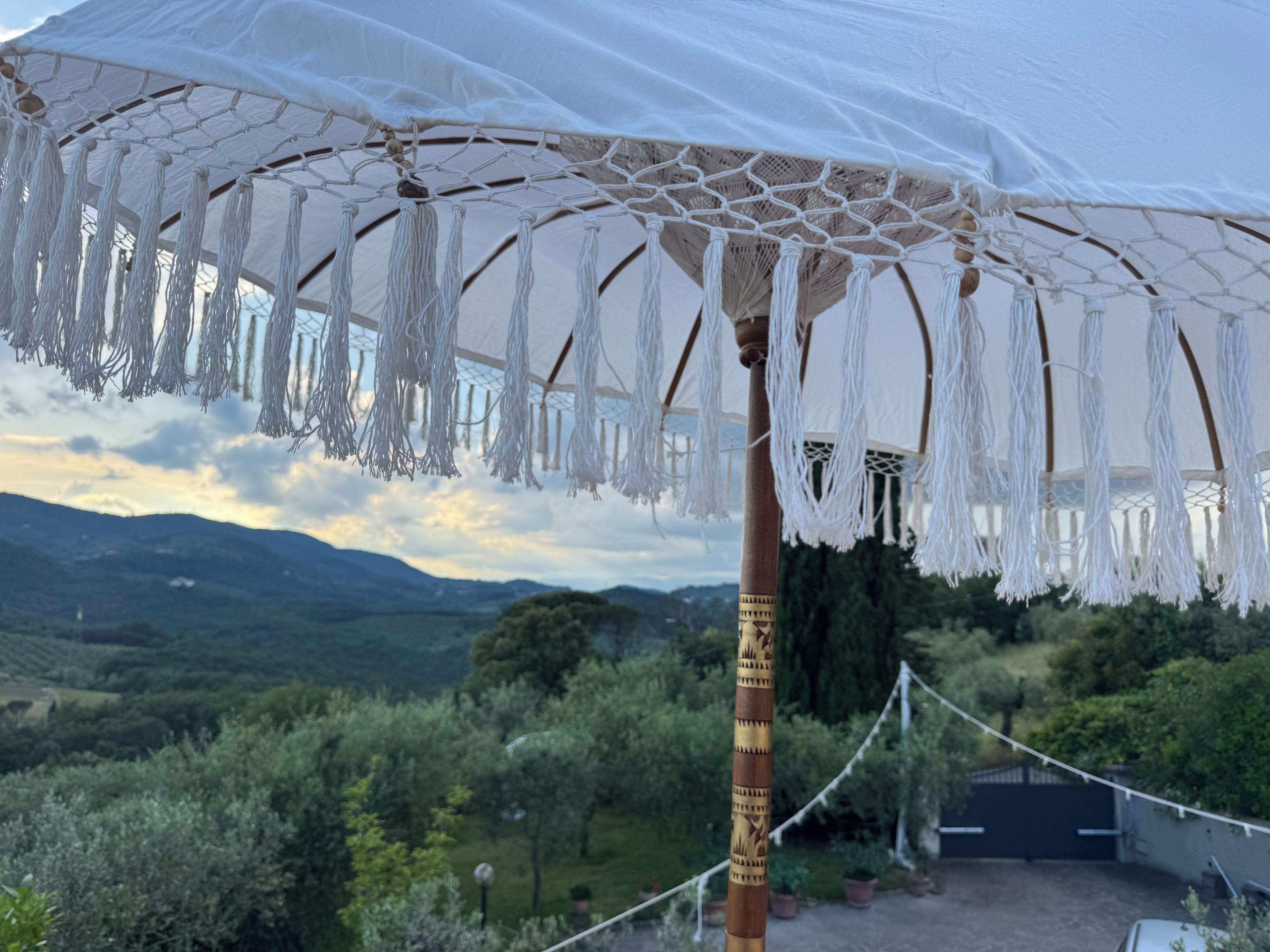 A view of a mountainous landscape with a white canopy structure featuring macrame details.