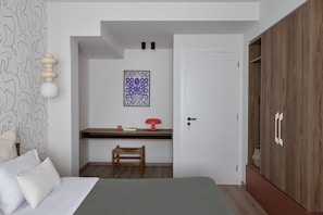 Een slaapkamer met een bed, een bureau, een stoel, een kledingkast en een muur met een poster.