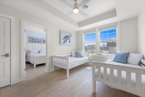 Ein Schlafzimmer mit einem weißen Bett, einer weißen Bank und einem Deckenventilator.