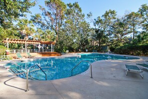 Piscina con sillas de descanso y una zona de estar cubierta.
