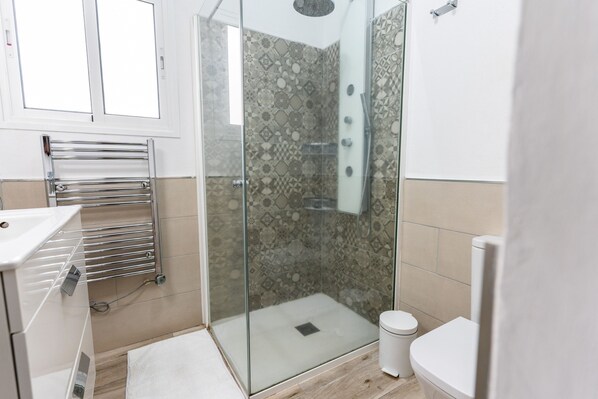 Ein modernes Badezimmer mit einer Duschkabine aus Glas, einem weißen Waschbecken und einer Toilette.