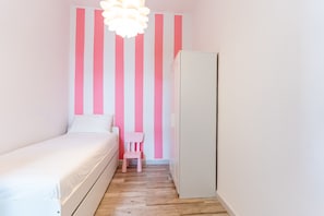 A bedroom with a bed, a chair, a wardrobe, and a wall with vertical stripes. - 3-Bedroom Smile Family Home (Los Llanos de Aridane)